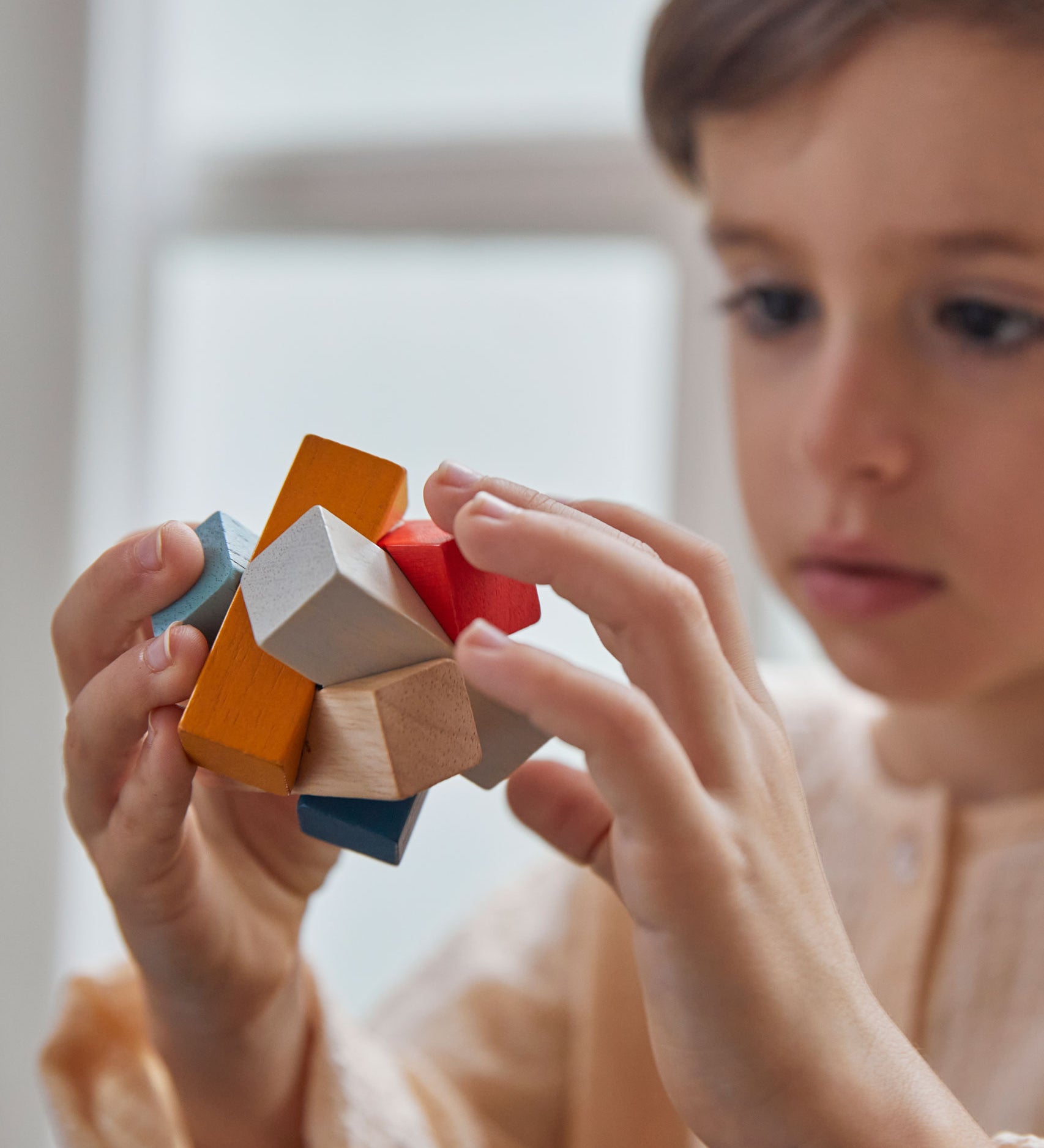 A close up of the PlanToys Waldorf toy block puzzle in a child's hands.