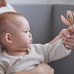 Close up of mother and baby holding the PlanToys wooden Shake N Clap baby rattle toy