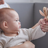 Close up of mother and baby holding the PlanToys wooden Shake N Clap baby rattle toy