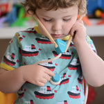 A child playing with the PlanToys Doctor Set, they have the stethoscope on and they are listing to their own heart.