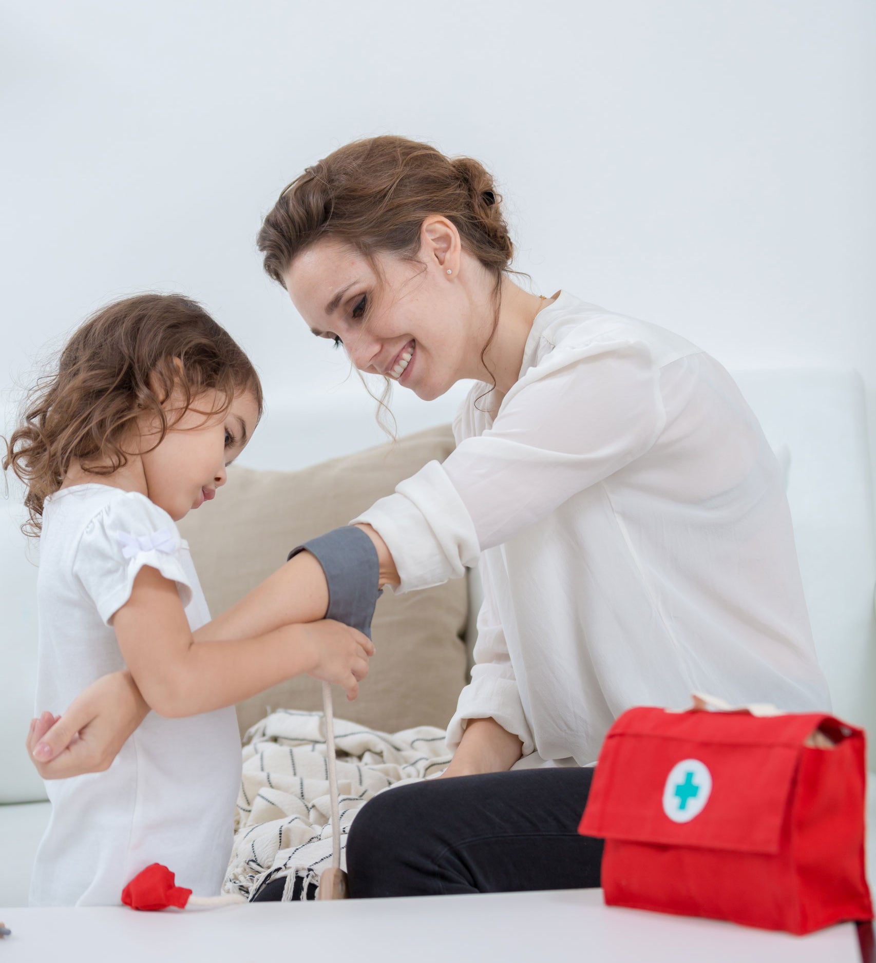 A child and adult playing with the PlanToys Doctor Set. The child is using the blood pressure cuff on the adult. 