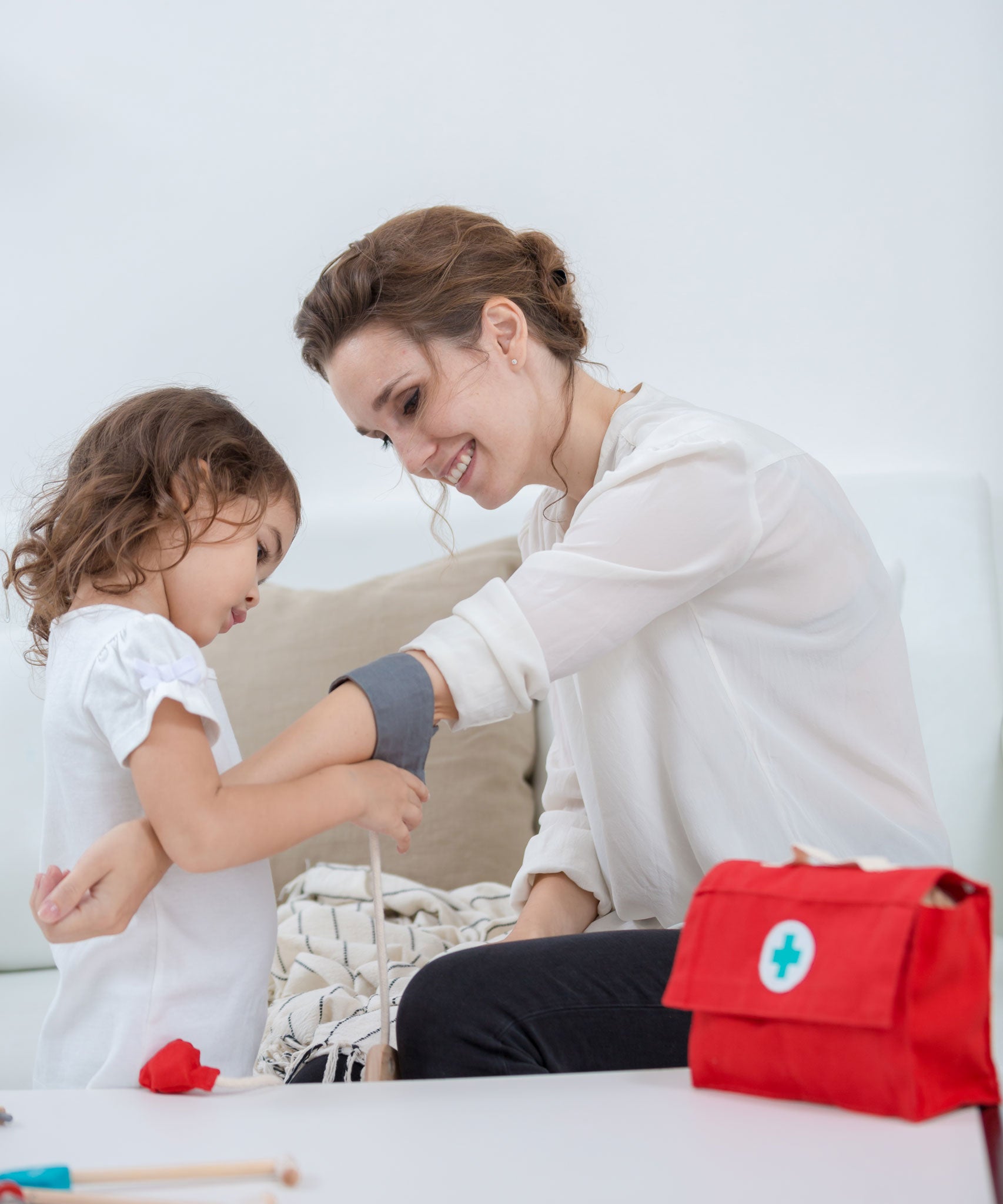 A child and adult playing with the PlanToys Doctor Set. The child is using the blood pressure cuff on the adult. 