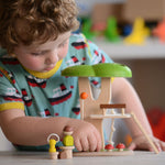 The PlanToys PlanWorld Tree House being played with by a child. The child's hand can be seen holding on to one of the little wooden toadstools. 