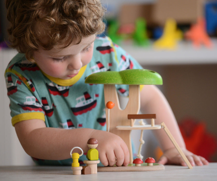 The PlanToys PlanWorld Tree House being played with by a child. The child's hand can be seen holding on to one of the little wooden toadstools. 