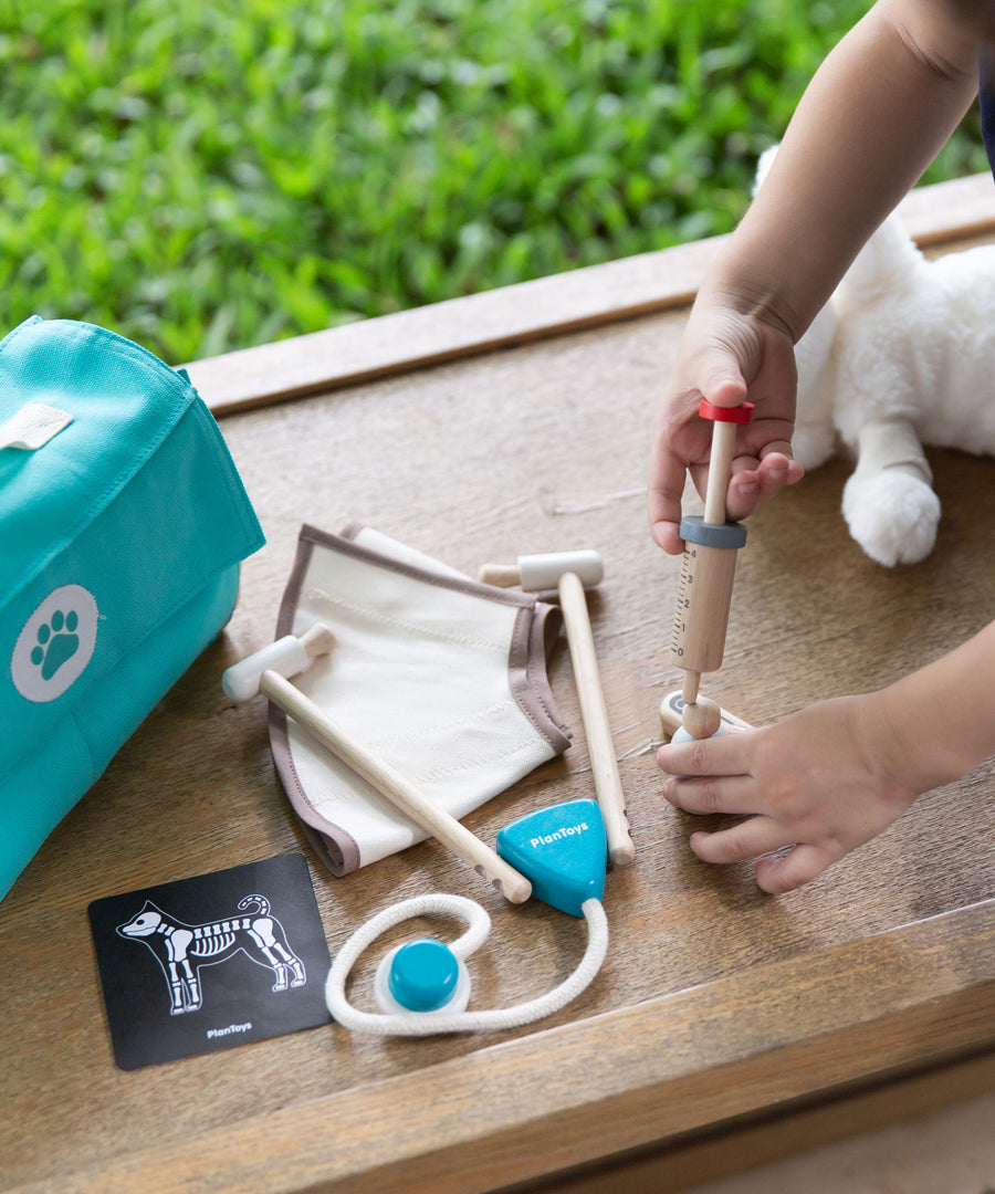 A close up of a child's hand playing with the Plan Toys Play Vet Set. 