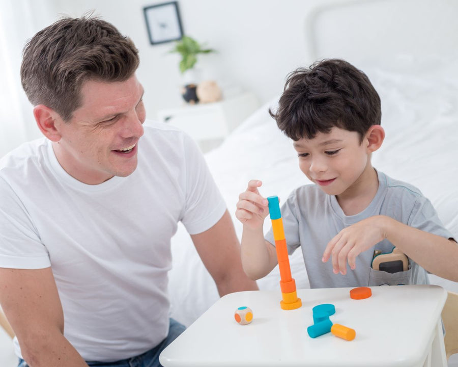 Close up of child stacking up the coins in the PlanToys mini stacking game.