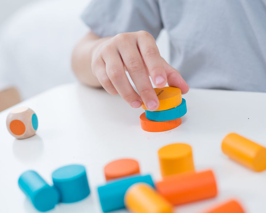 Child playing with the PlanToys mini stacking game on a small table.