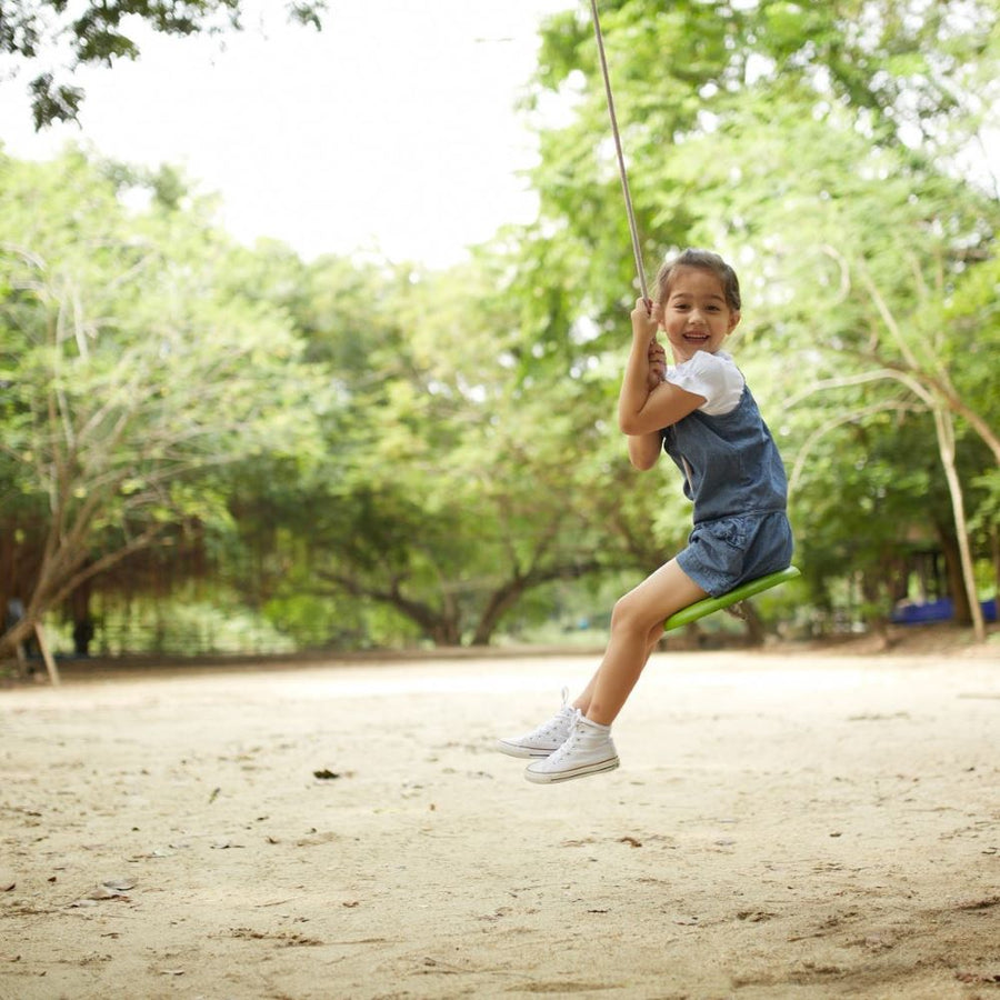 Child swinging outside on the PlanToys Saucer Disc Swing