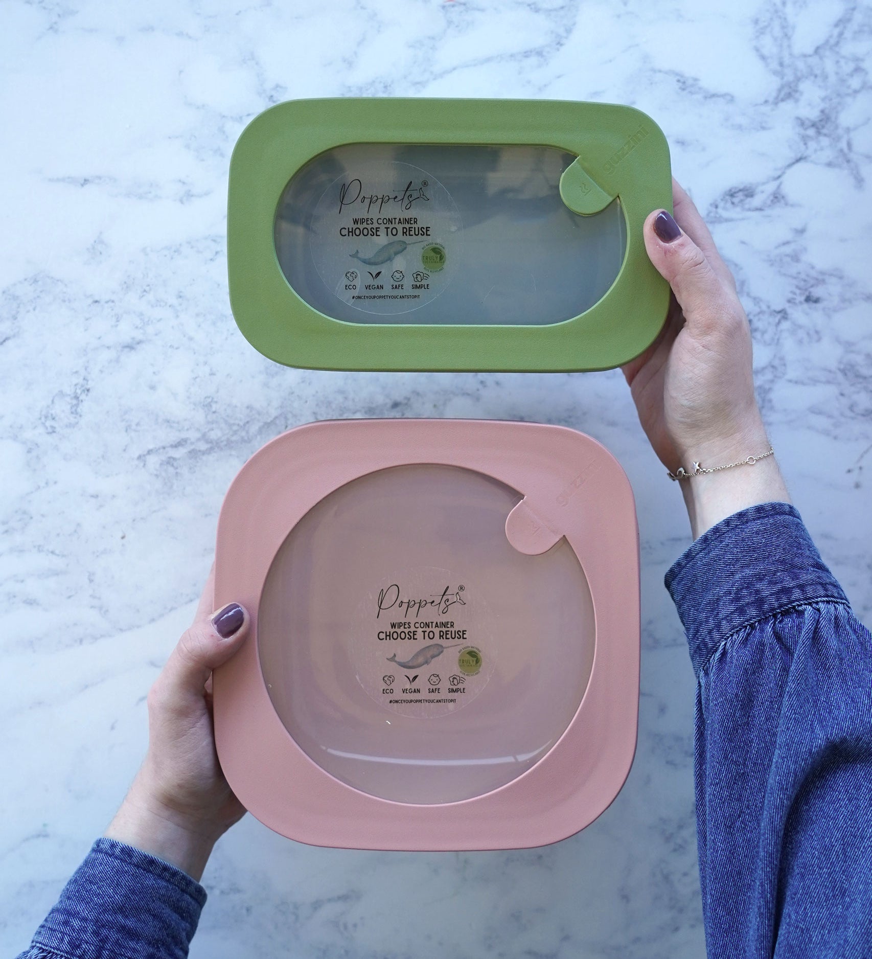 A green poco small reusable wipes container next to a pink grande container in a person's hands.