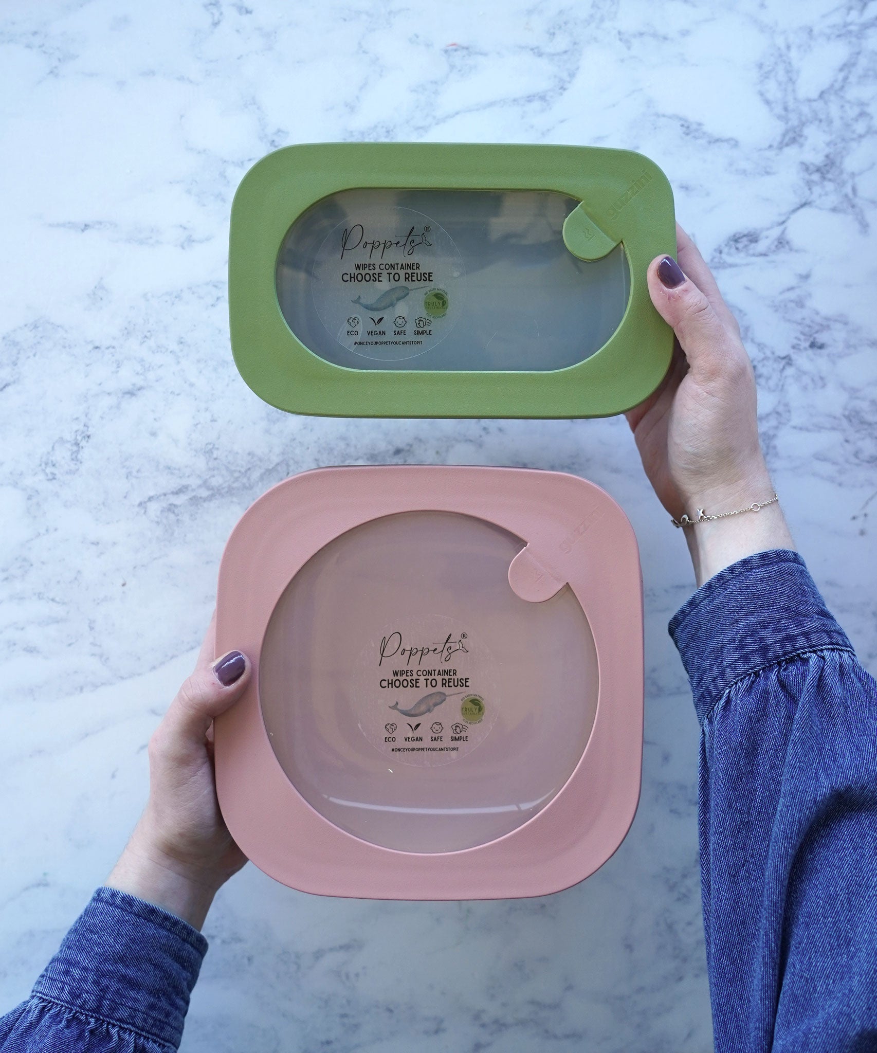 A green poco small reusable wipes container next to a pink grande container in a person's hands.