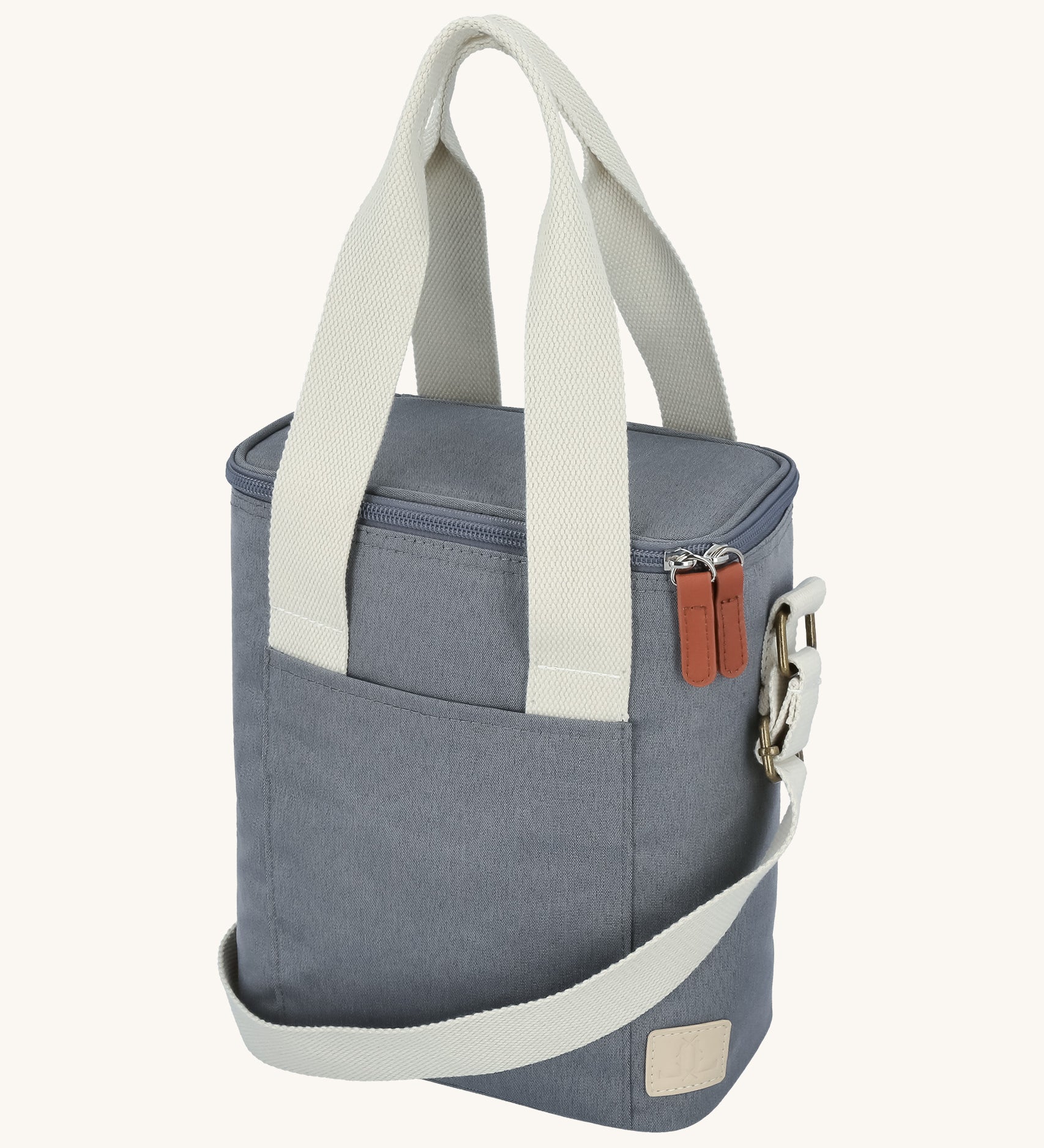 The Lola & Lykke Milk Cooler Bag on a cream background. The bag is denim blue in colour with white carry straps and shoulder strap