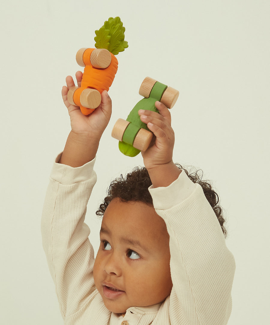 A child holding the Cathy Carot and thr Pepino the Pickle car above their head in their hands