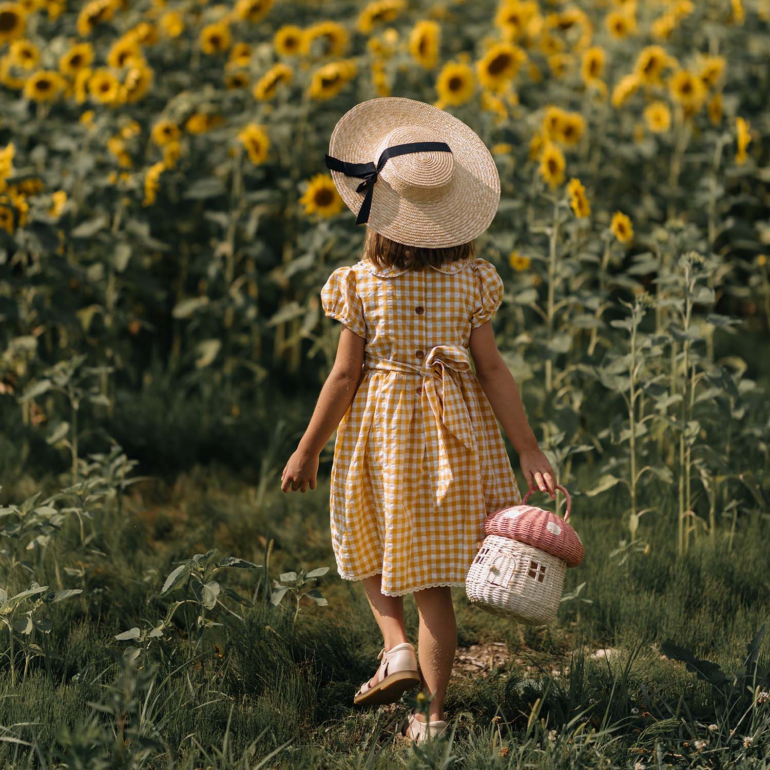 Picture of a child holding the Olli Ella Mushroom Rattan basket with a spotted pink mushroom cap