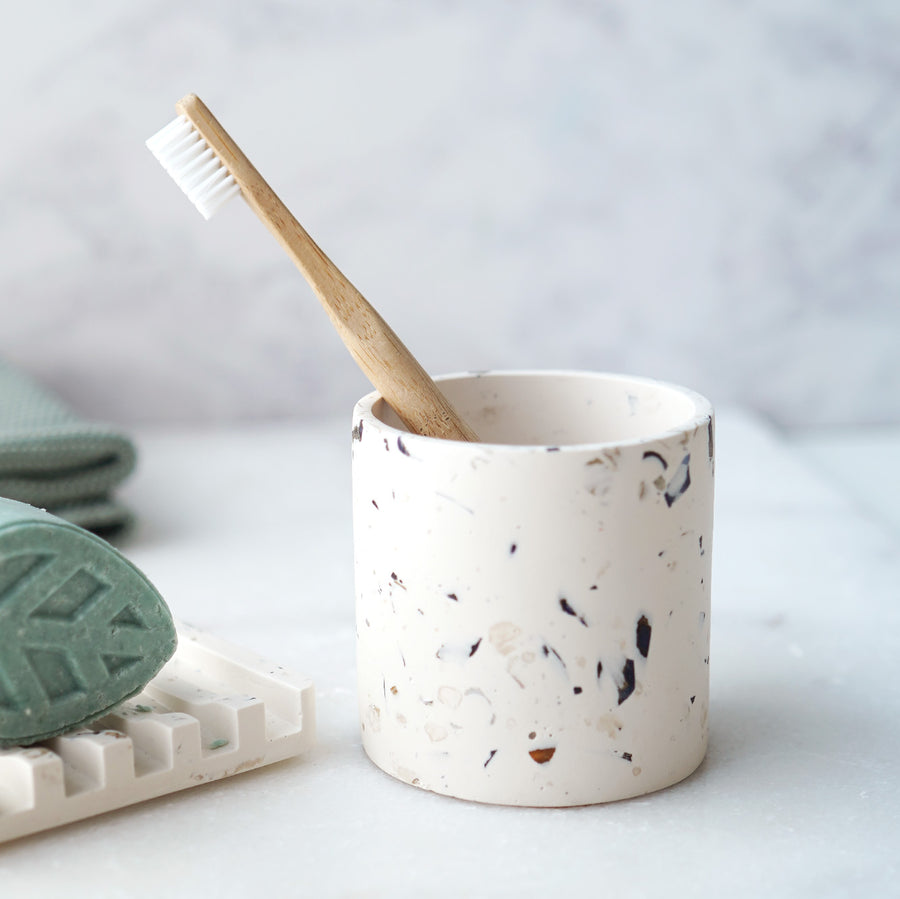 Rawr Shell Terrazzo Round Storage Pot in a bathroom setting. The pot holds a toothbrush and sits next to a soap bar and dish.