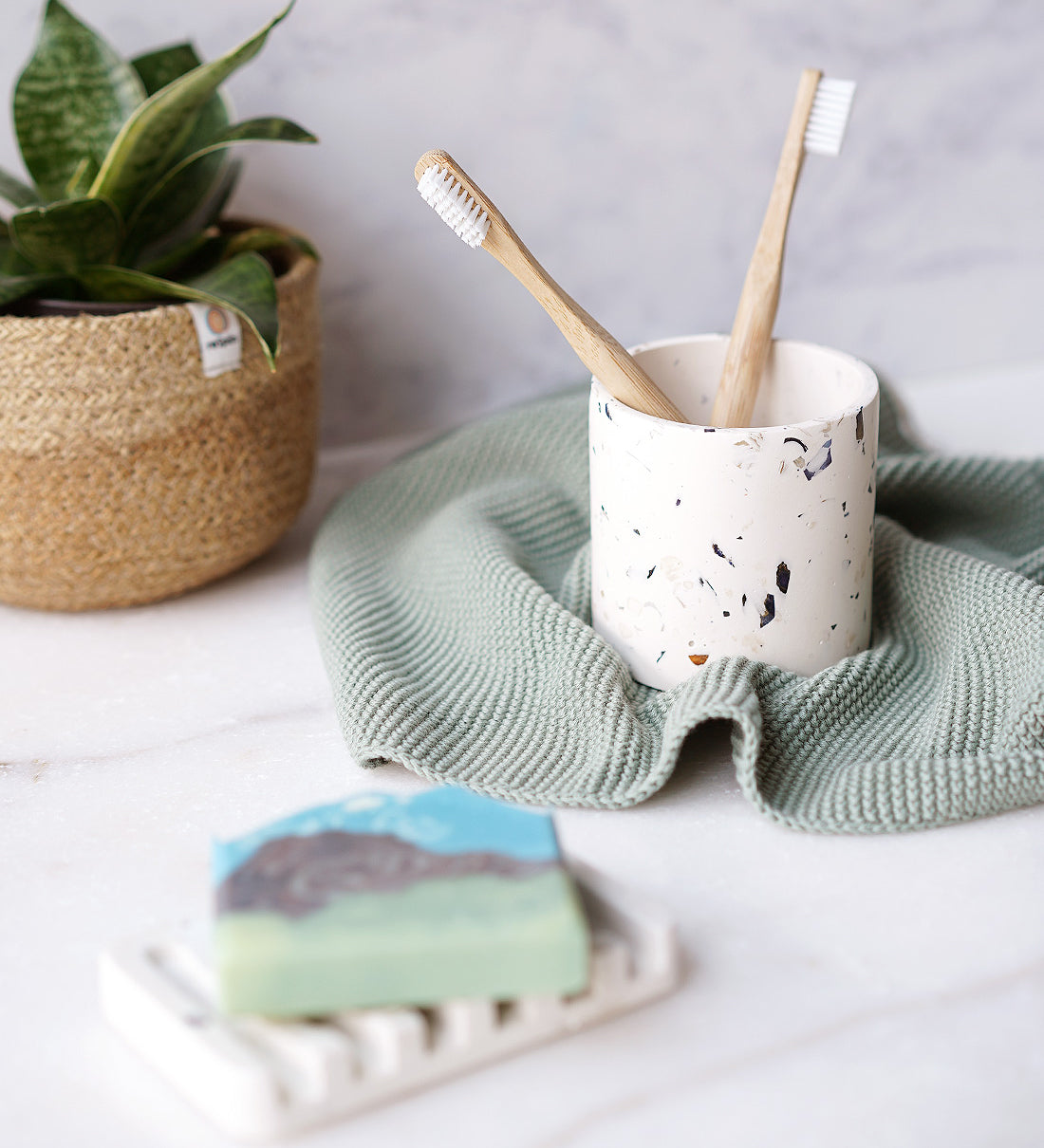 Rawr Shell Terrazzo Round Storage Pot in a bathroom setting. The pot holds two toothbrushes and sits next to a soap bar