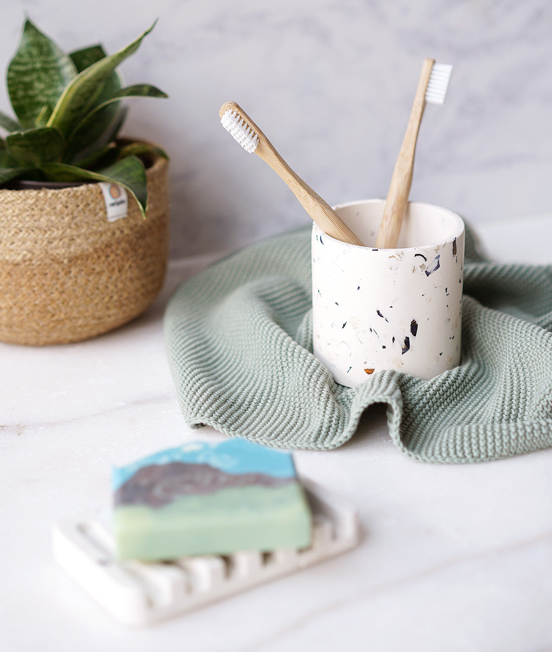 Rawr Shell Terrazzo Round Storage Pot in a bathroom setting. The pot holds two toothbrushes and sits next to a soap bar