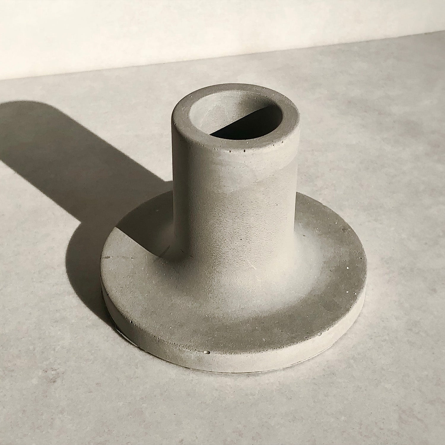 Rawr Grey Concrete Candlestick on a concrete surface and background.