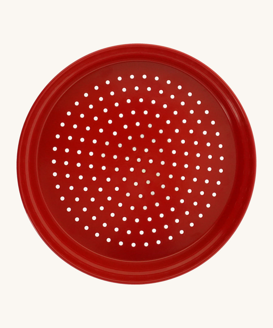 Red metal sand sieve on a cream background