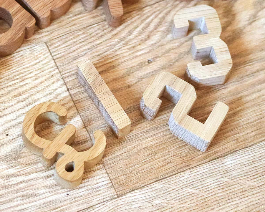 Reel Wood Pound symbol laying on a wooden floor next to some Reel Wood Numbers