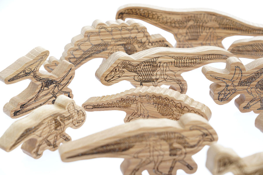 Close up of the handmade plastic free reel wood dinosaur figures on a white background