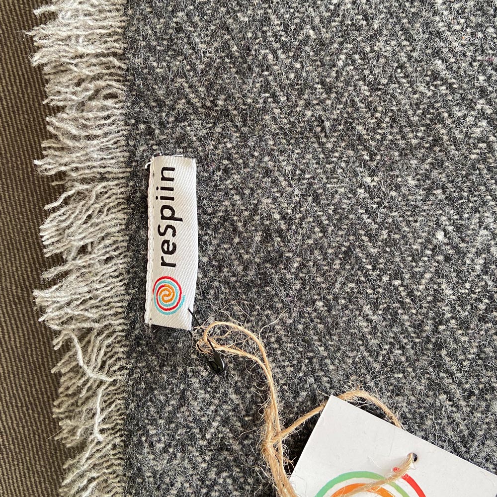 Close up of the Respiin label on the recycled grey wool throw blanket