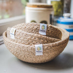 A set of three natural ReSpiin Jute Mini Bowl Set shown nestled inside each other on a window sill