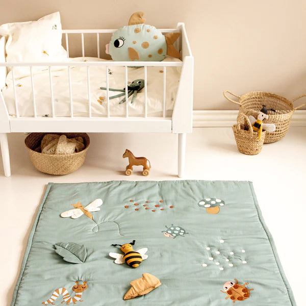 Roommate Baby Bugs Activity Blanket in a Sea Grey colour pictured on the floor of a nursery room