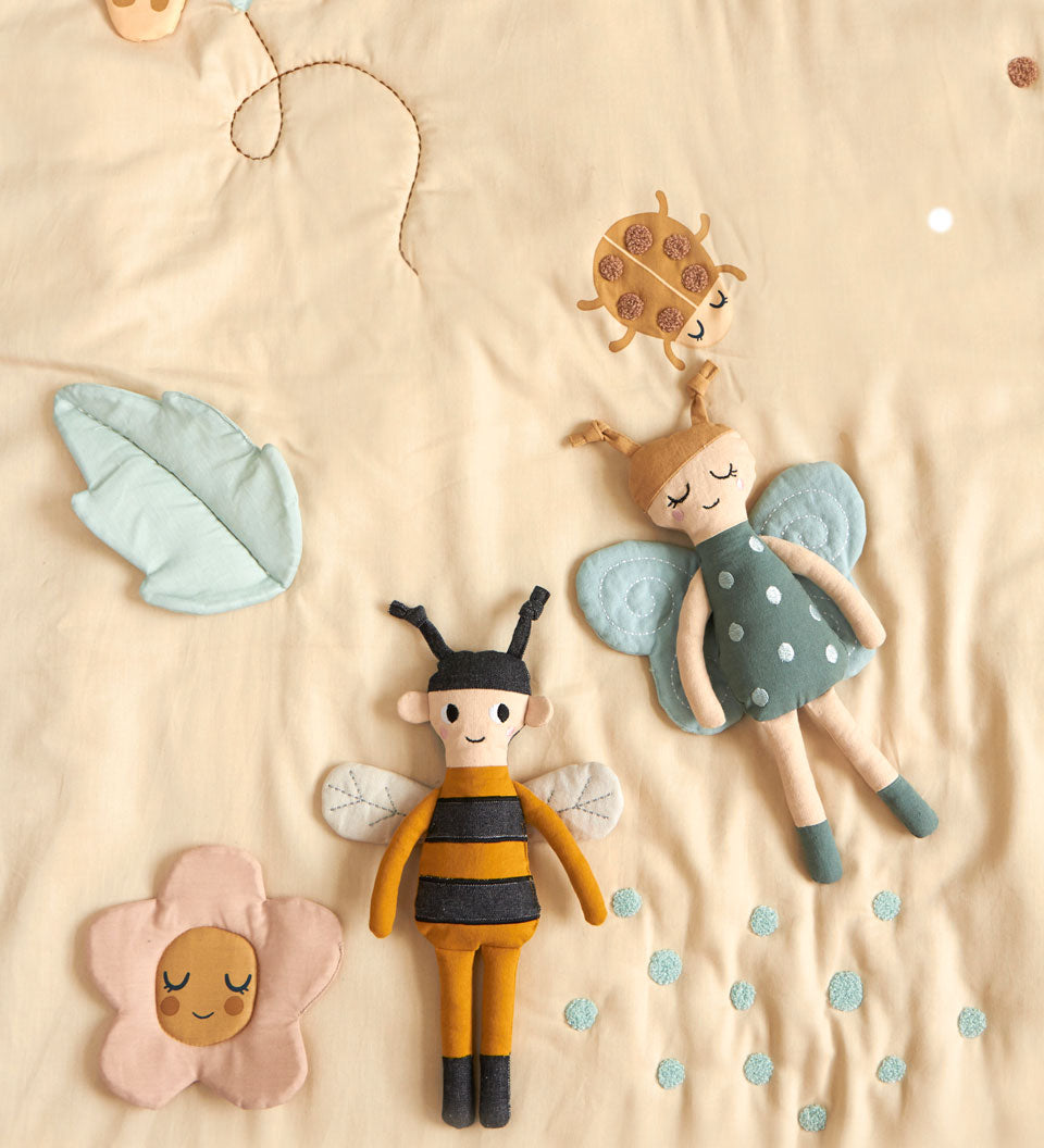 Childrens Roommate eco-friendly soft rag doll bee and butterfly toy laying on a cream duvet set