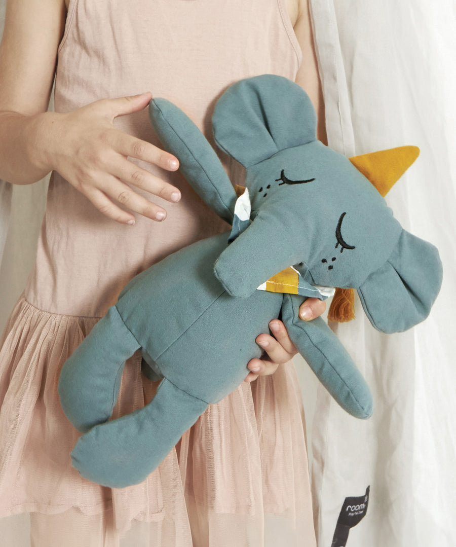 A close up of a child holding onto a Roommate Eddy The Elephant Canvas Doll.