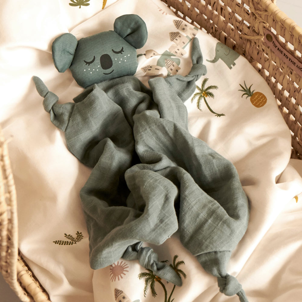 Roommate eco-friendly soft koala baby comfort blanket laid out on a white duvet in a moses basket