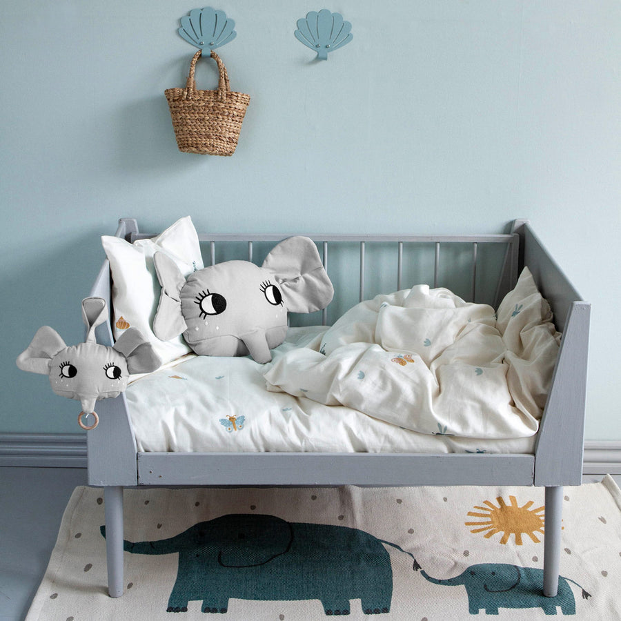 Roommate organic cotton elephant cushion in a grey wooden children's bed on some white bedding