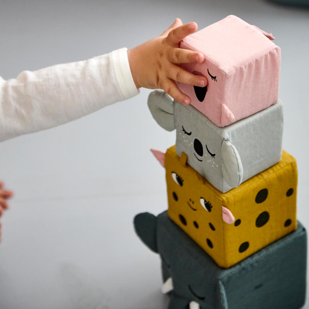 A close up of a child's hand on the pink flamingo block from the Roommate Jungle Life Stacking Blocks.