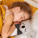 A child sleeping next to a Kody The Koala canvas doll.