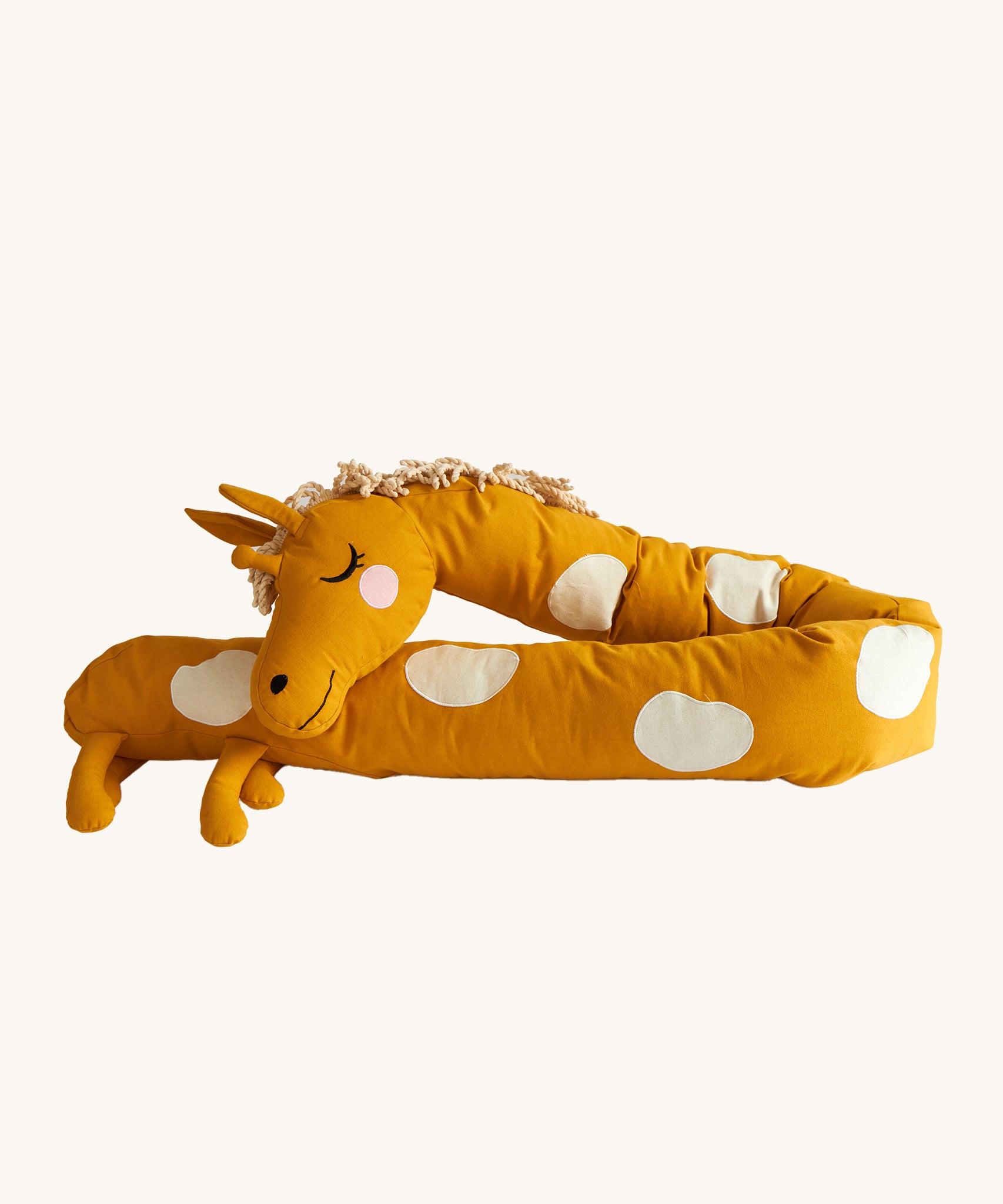 Roommate Long Organic Giraffe Cushion. A sleepy, smiling, long giraffe cushion in mustard yellow with cream spots, a curly mane and 4 small legs