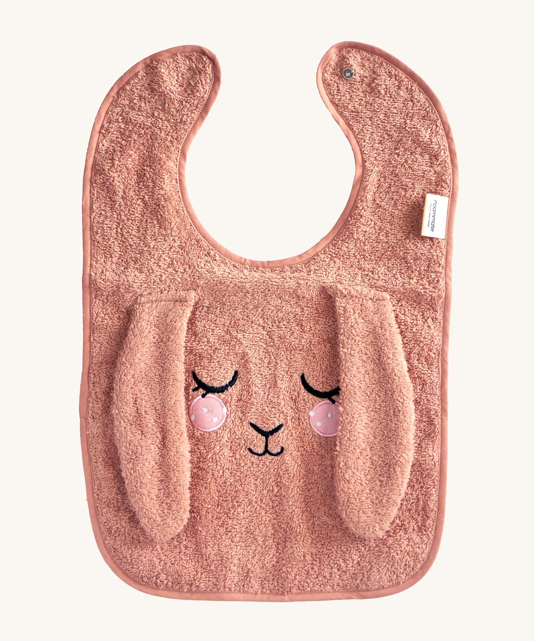 Roommate Baby Bib - Bunny in a soft, pale pink fabric, with a sleepy embroidered face and soft, floppy ears