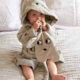 A baby wearing the Roommate grey mouse bathrobe dressing gown, and holding a Roommate comforter toy. 