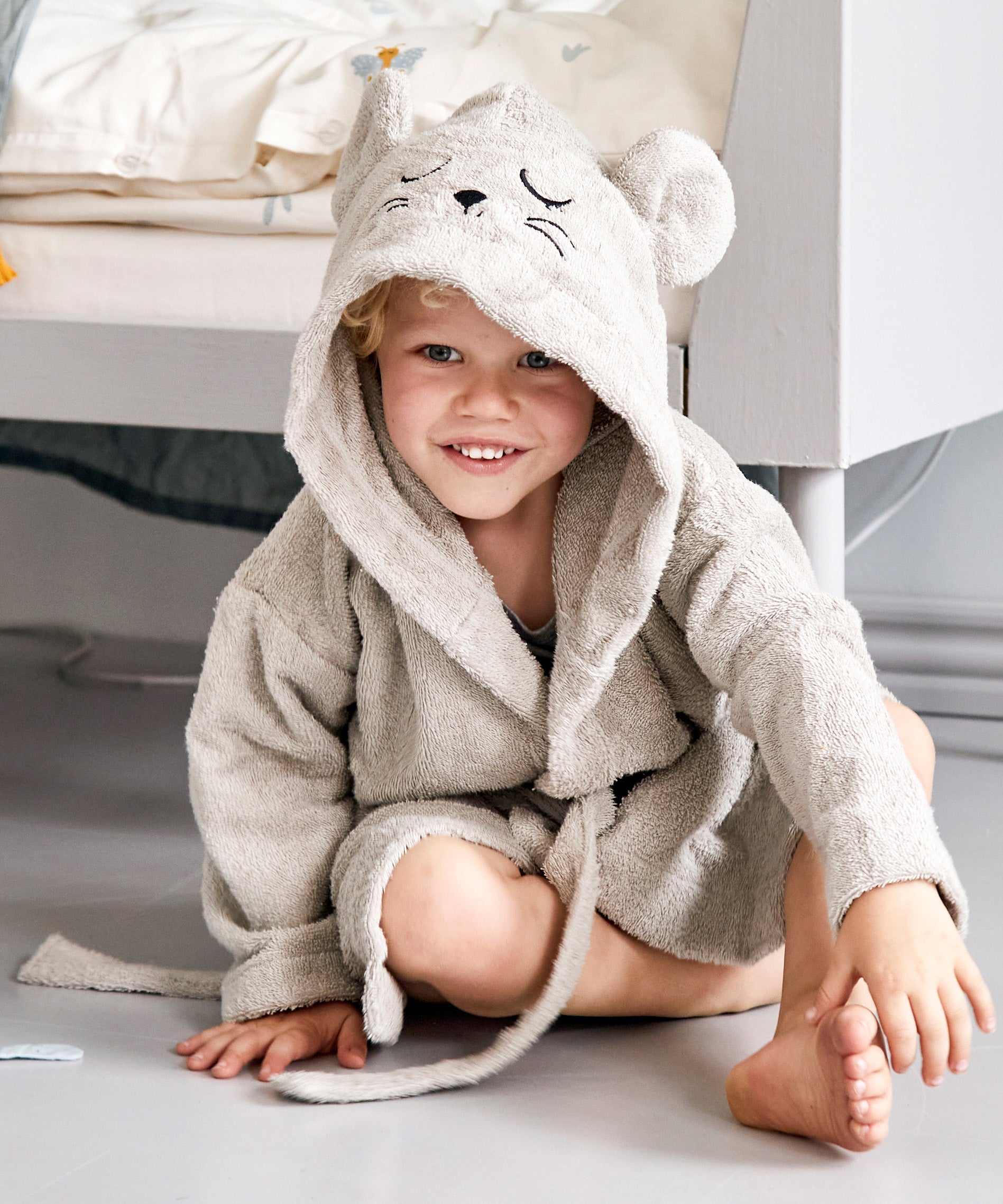 A child wearing the Roommate mouse bathrobe in a bedroom. 