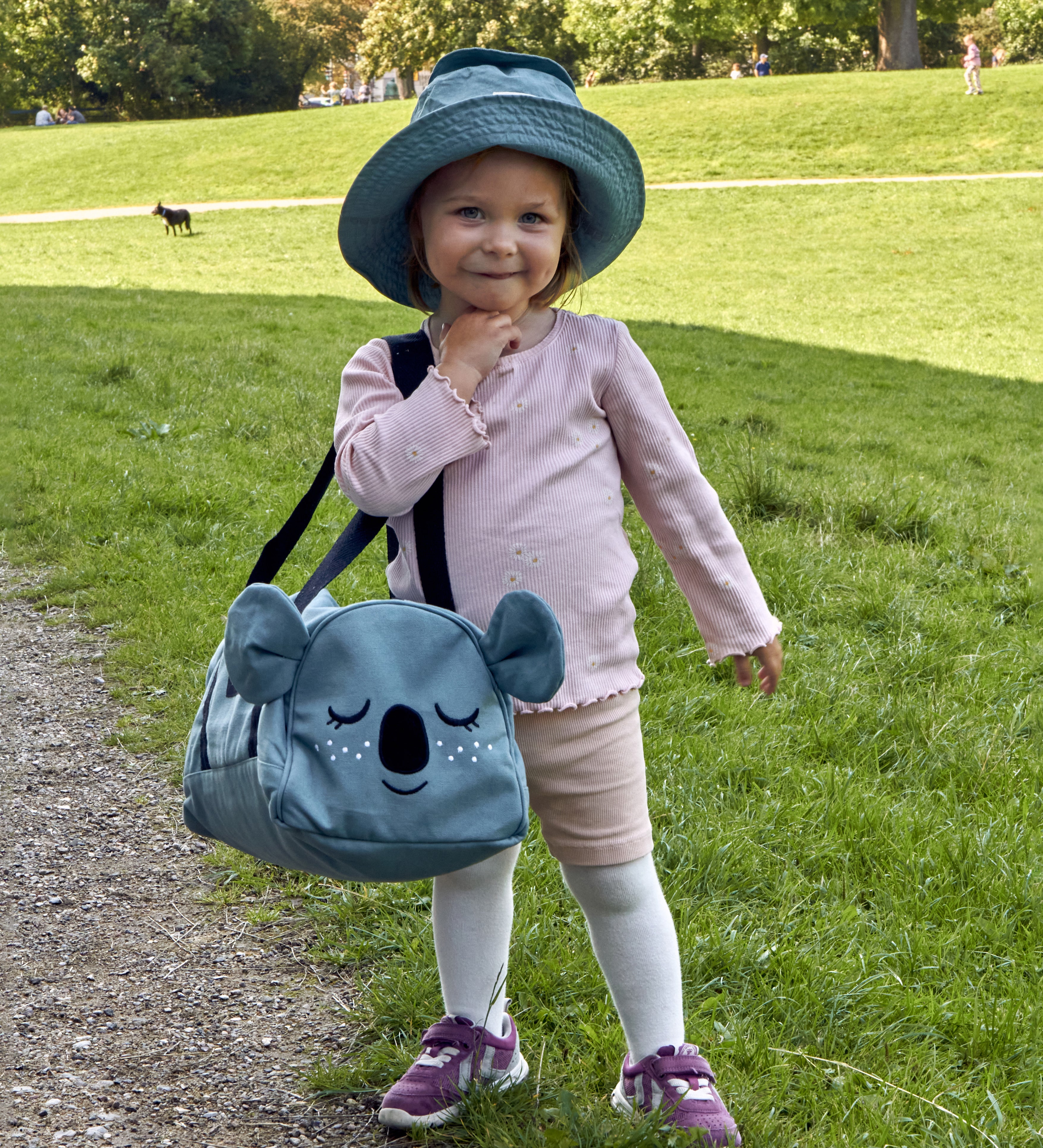 A child wearing the Roommate Koala bucket hat and carrying a koala bag.