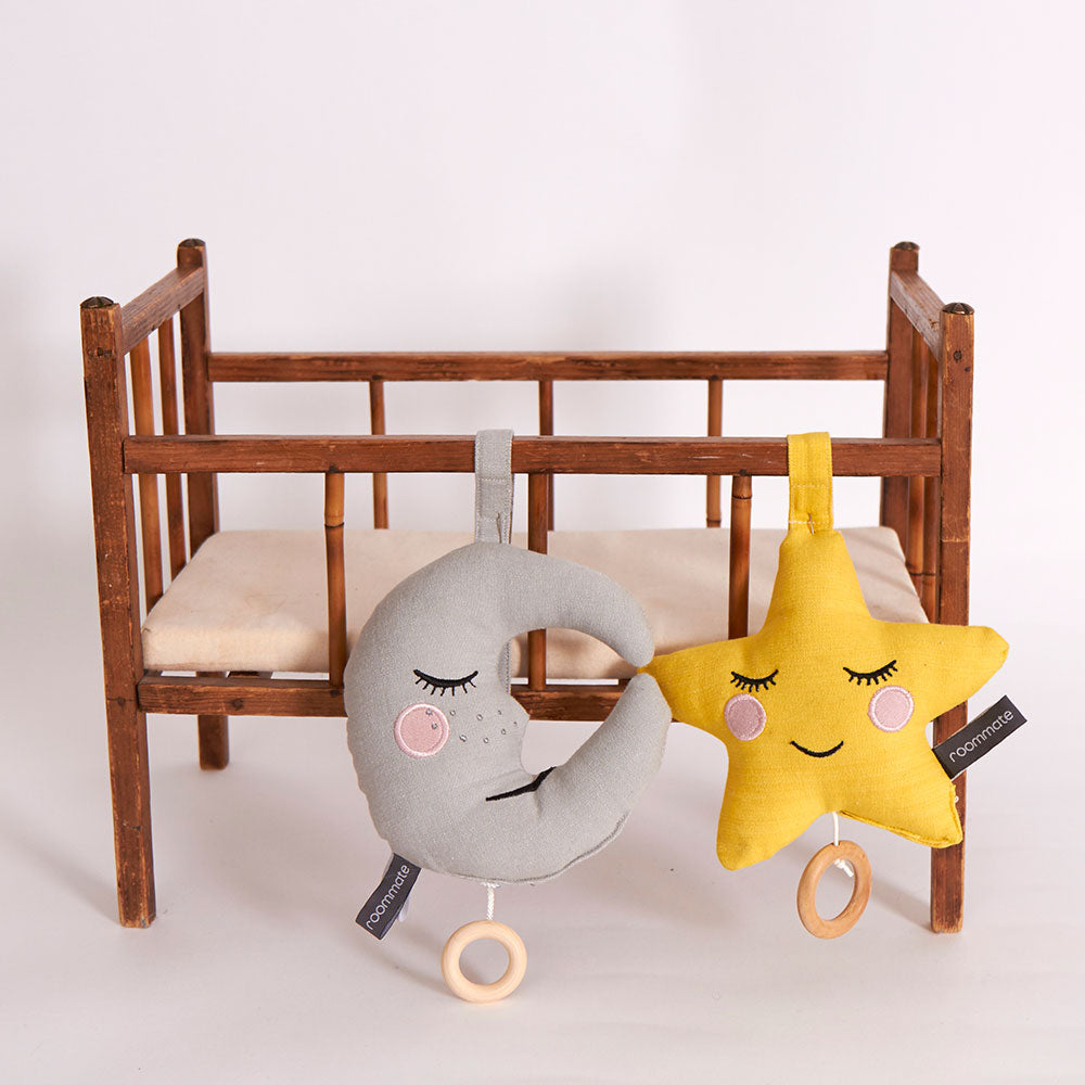 A star and moon Roommate Lullaby Music Mobiles hung on a little toy wooden bed.