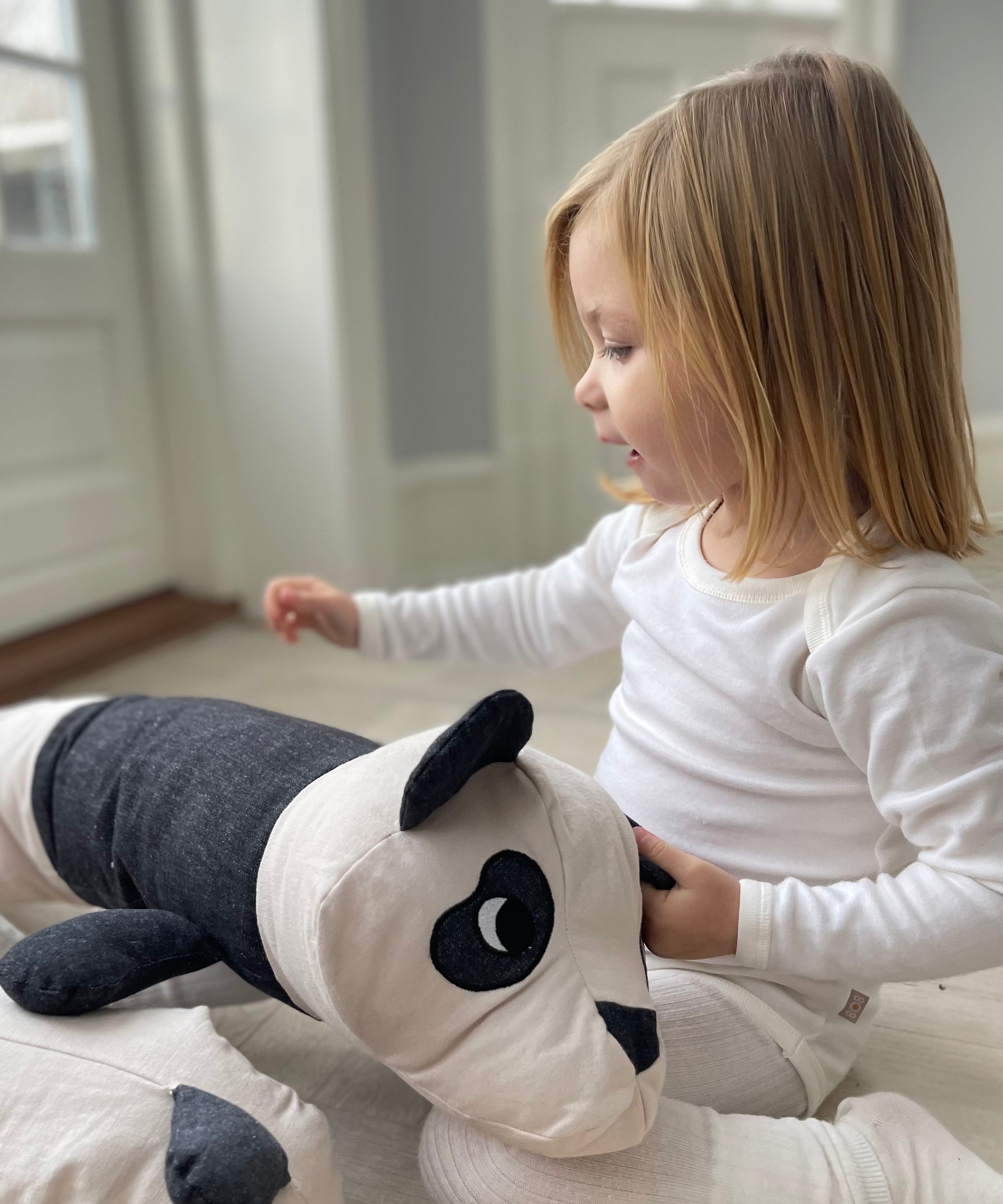 A child playing with the long roommate panda cushion