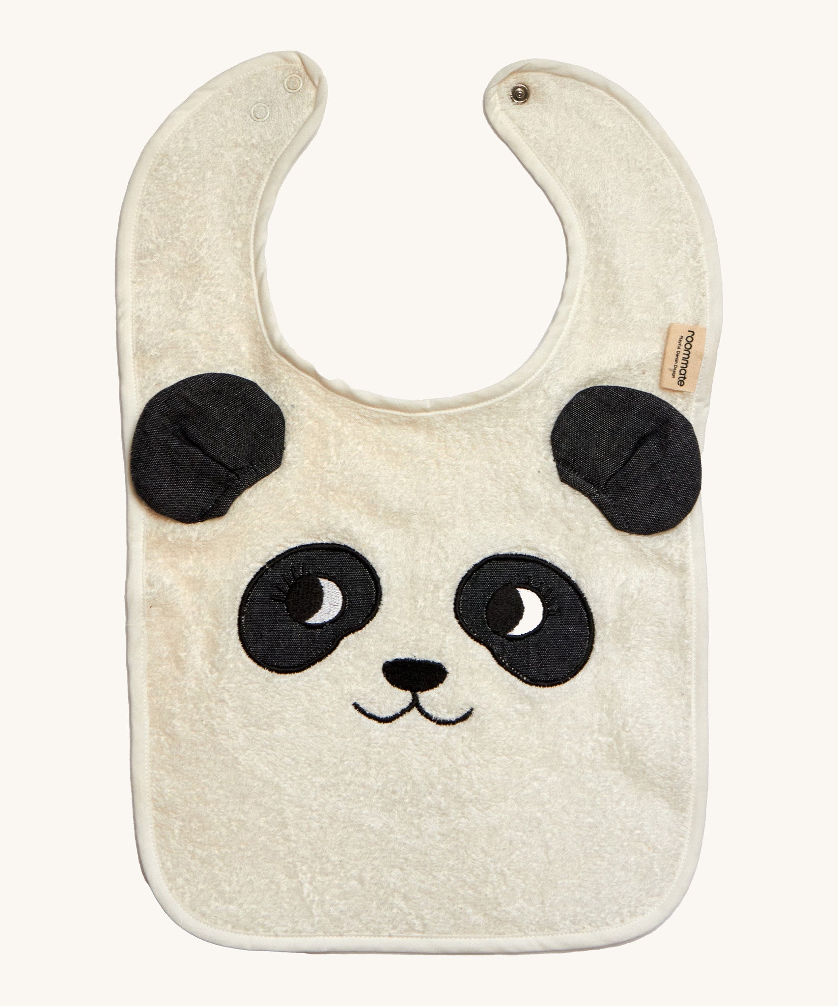 The Roommate Panda Baby Bib in organic cotton with embroidered panda face with 3D ears. Cream background.