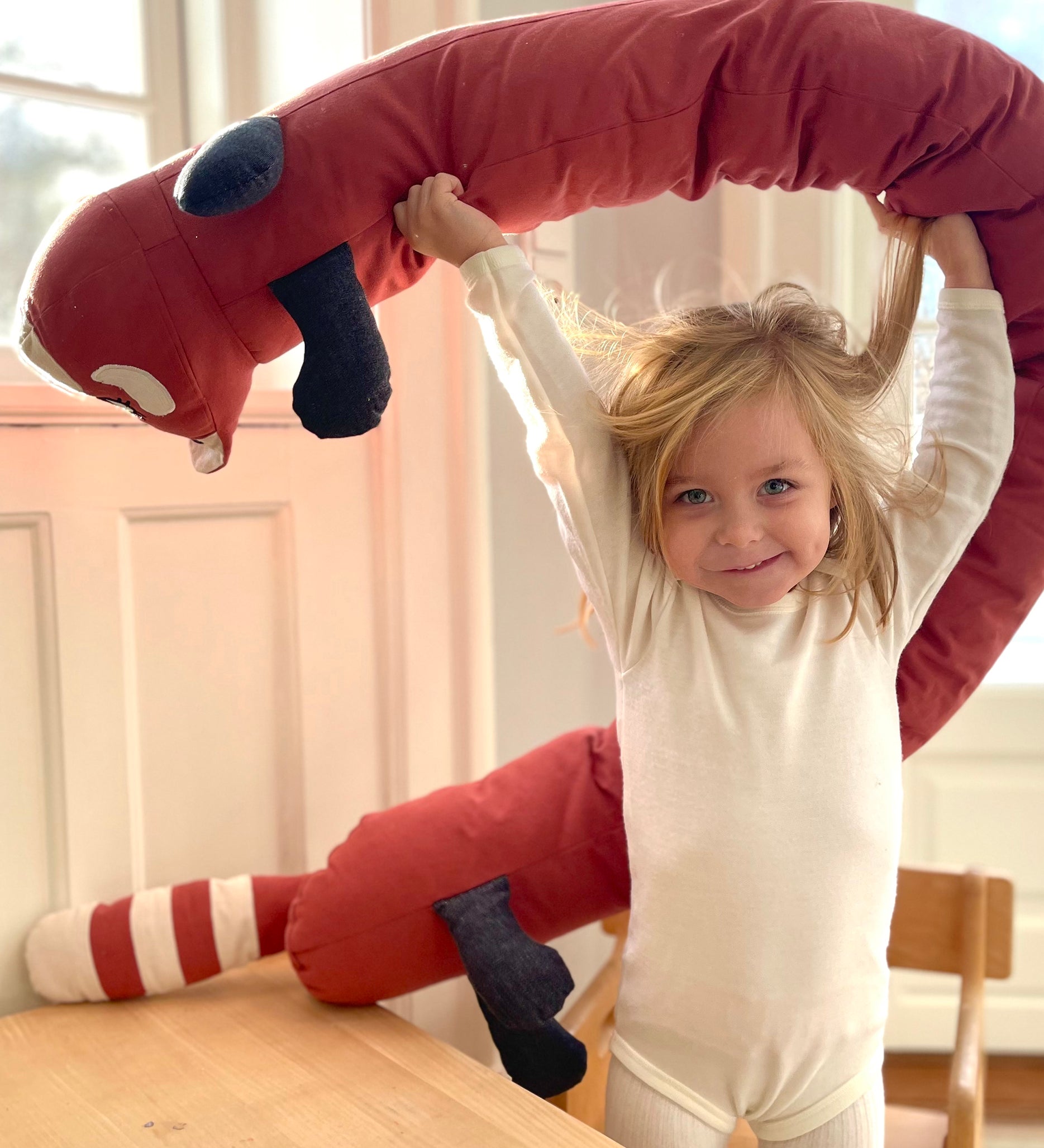 A child holding the Roommate red panda cushion above the head 