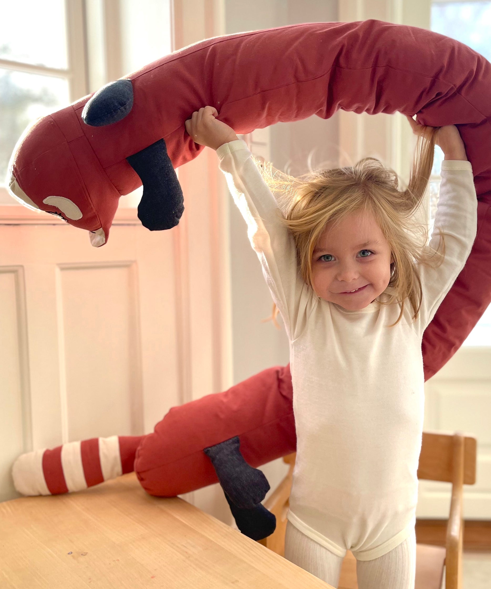 A child holding the Roommate red panda cushion above the head 