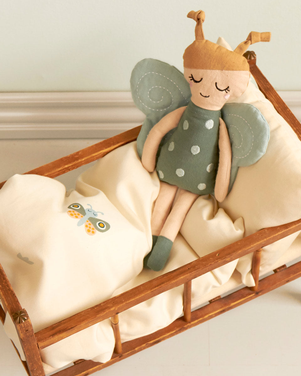 Roommate organic cotton kids soft butterfly rag doll toy laying in a toy cot