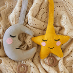 Two Roommate Lullaby Music Mobiles on a knitted blanket, one moon and one star. 