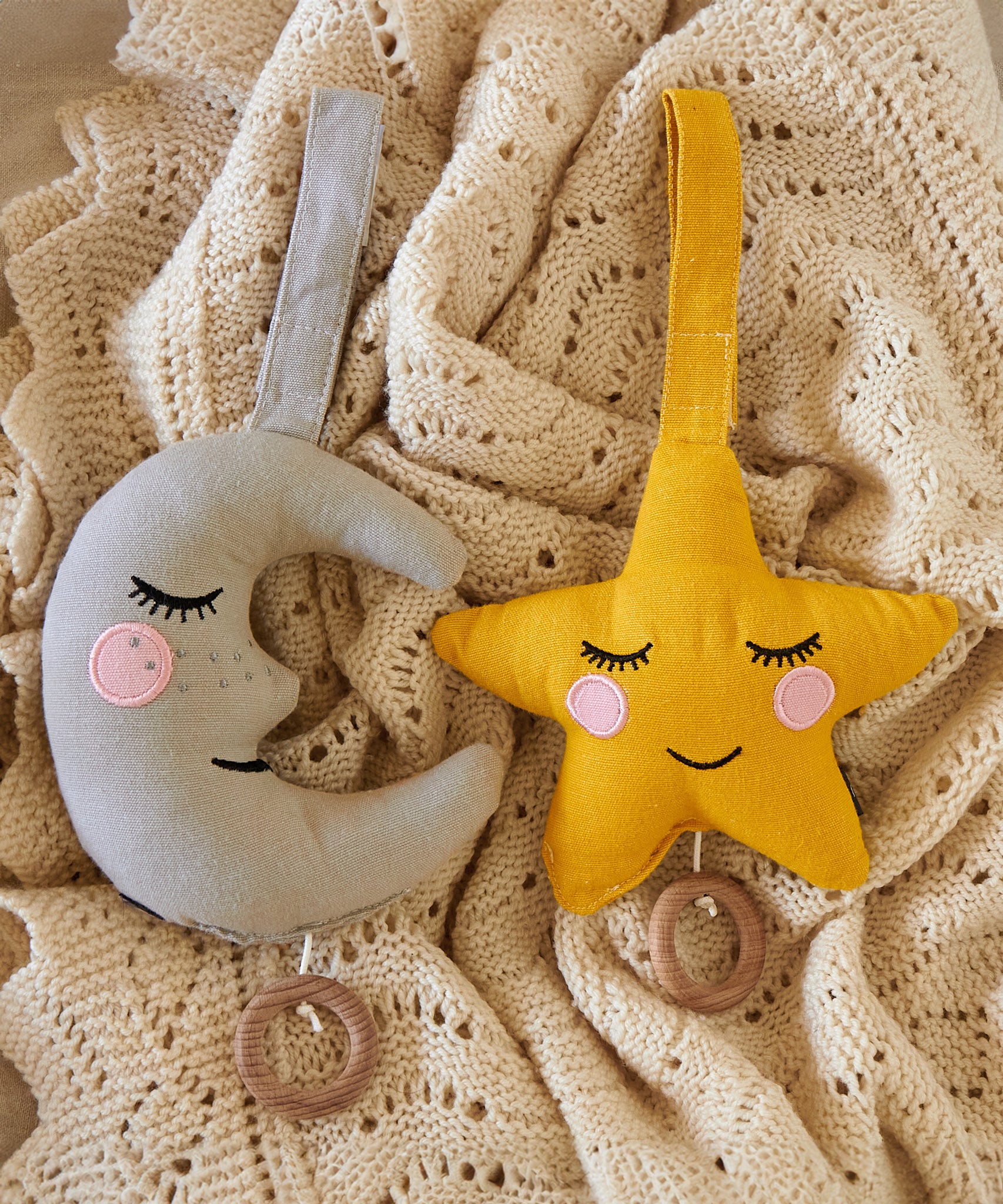 Two Roommate Lullaby Music Mobiles on a knitted blanket, one moon and one star. 