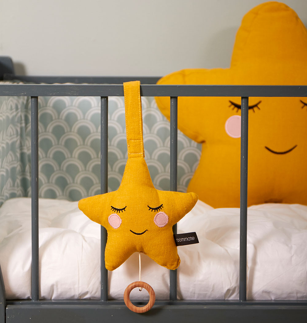 A Roommate Star Lullaby Music Mobile hung on the side of a cot. 