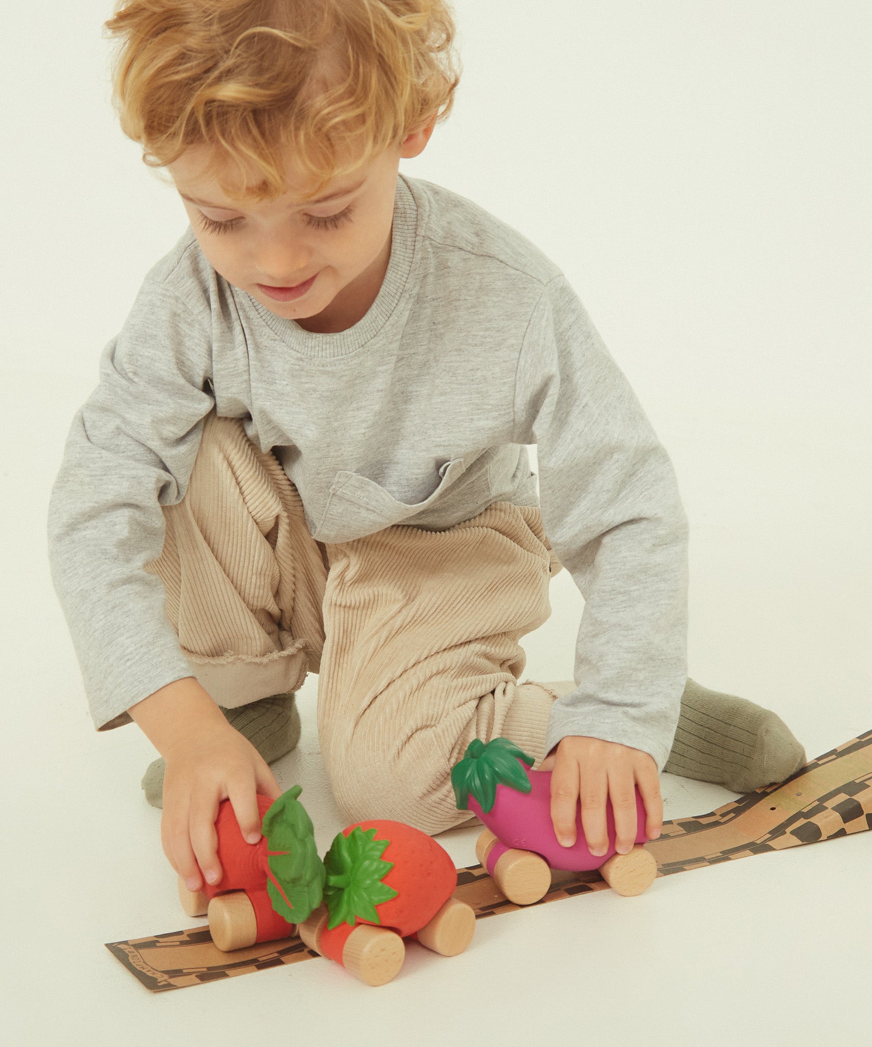 A child holding the Oli & Carol 100% Natural Rubber Car collection