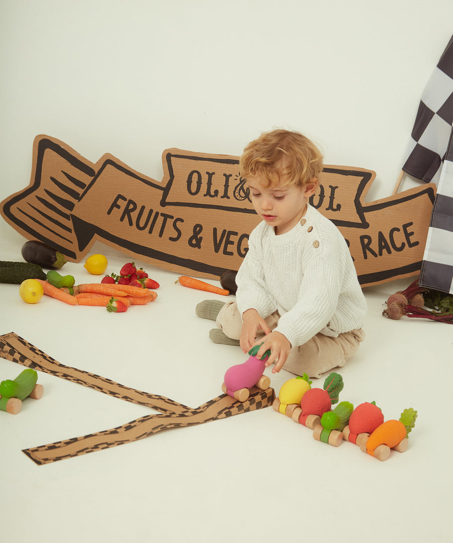 A child holding the Oli & Carol 100% Natural Rubber Car collection