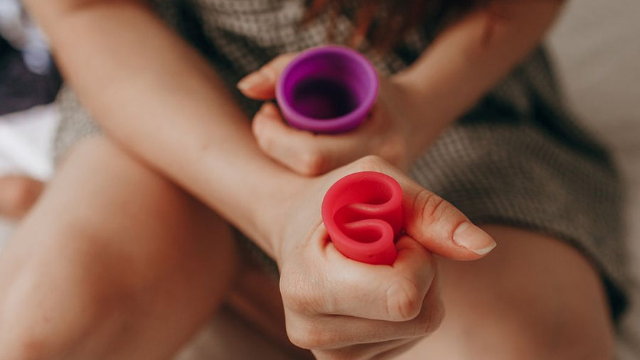 Woman squeezing two Ruby menstrual cups